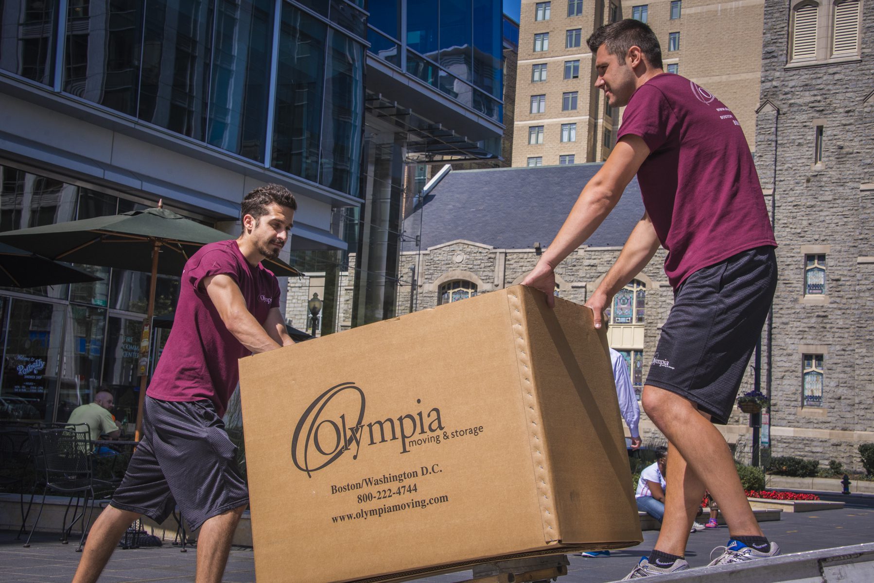 2 Olympia moving staffs carrying a large box
