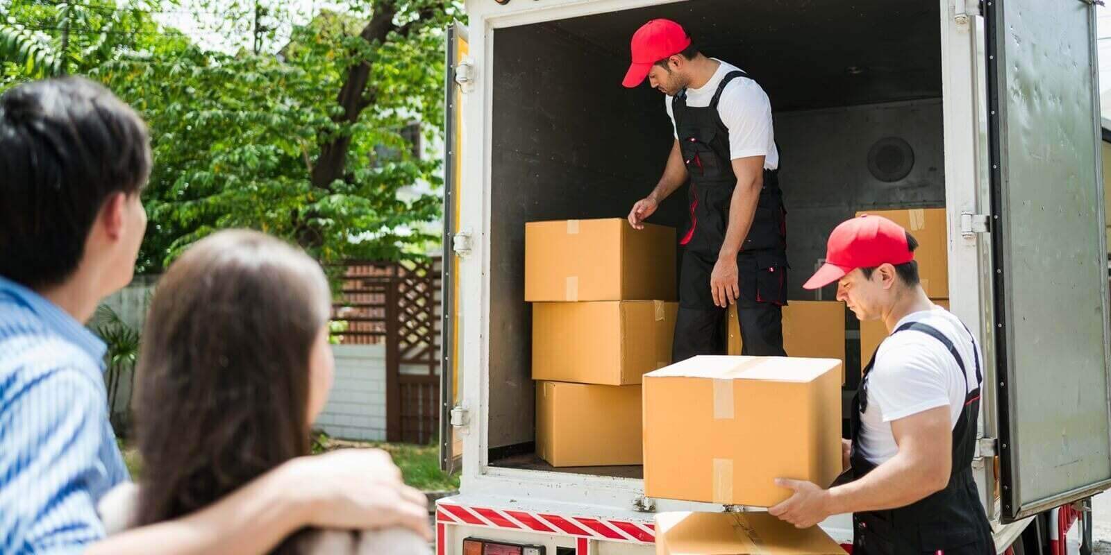 asian and caucasian workers in uniform unloading cardboard boxes from the truck