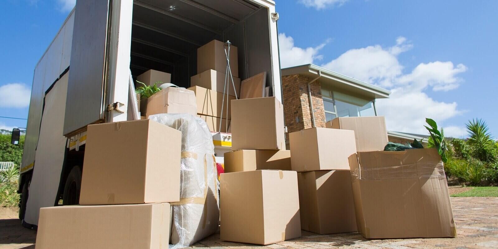 cardboard boxes outside moving van and house in sunny driveway