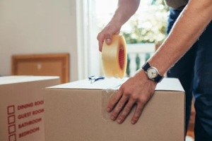 close up of a man applying adhesive tape on a packing box