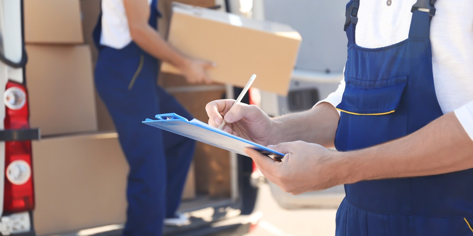 delivery man checking list on clipboard near car