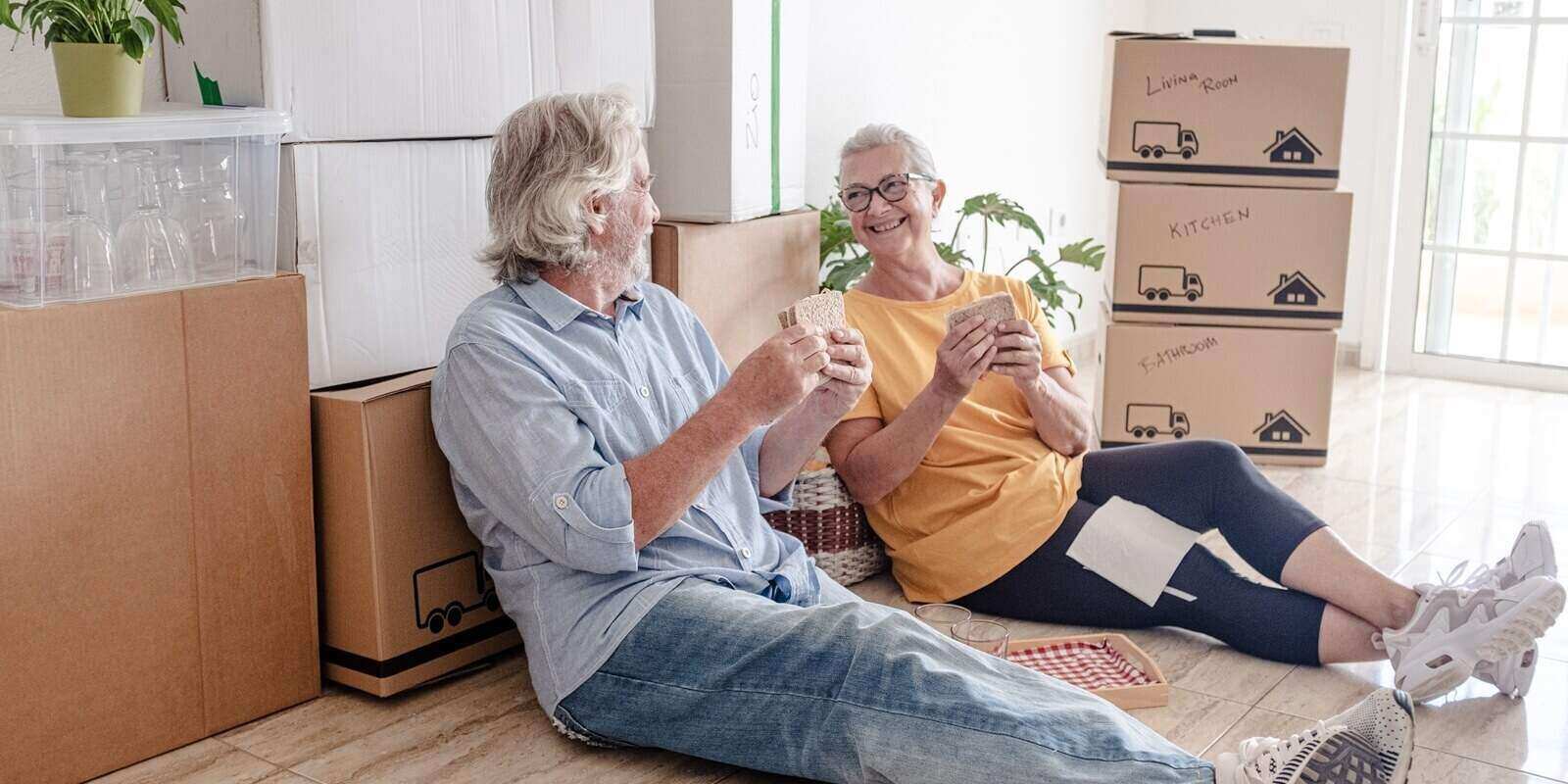 elderly couple moving into a new home, sitting on the floor for a break