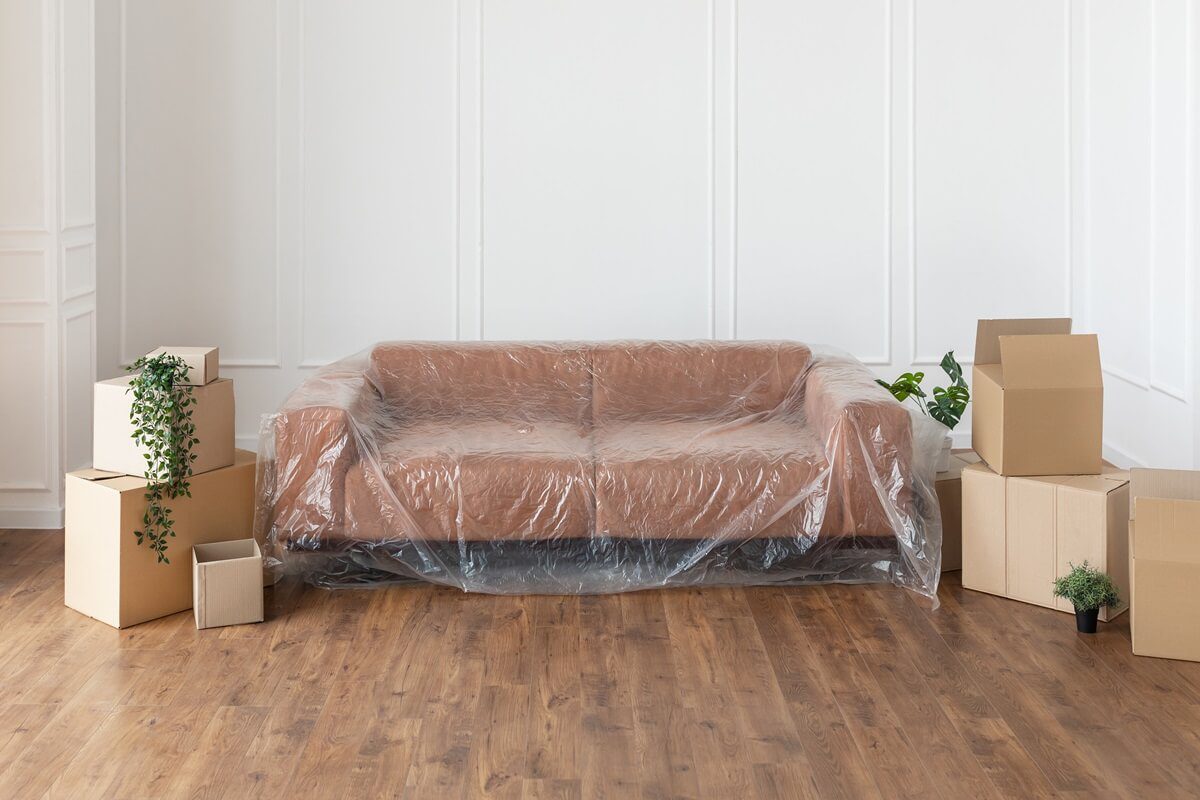 living room with covered sofa, stacks of boxes during relocation