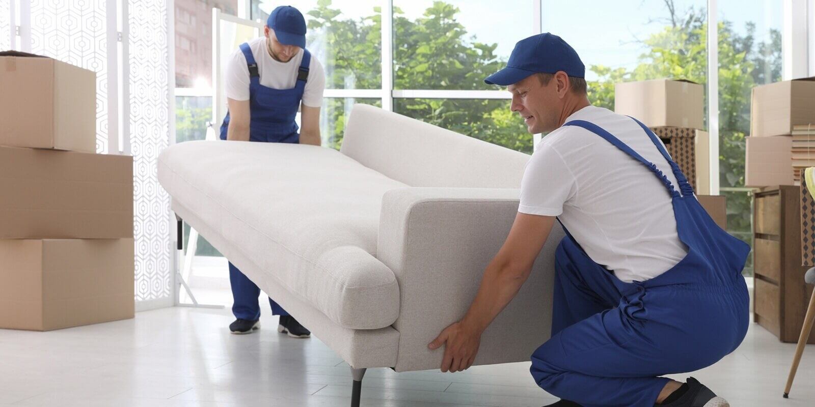 moving service employees carrying sofa in room