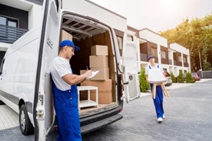 two removal company workers are loading boxes and furniture into a minibus